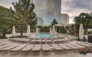 a pool with chairs and umbrellas and a building at ARIA Resort & Casino in Las Vegas
