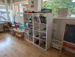 a book shelf in a classroom with a table and chairs at Auberge de nos Aieux in Les Éboulements