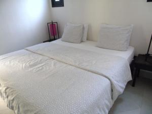 a white bed with white sheets and pillows at La Maison Nature Relax, Explore, Unwind in Asguine