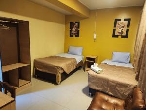 a hotel room with two beds and a chair at Hotel Palace in Huancayo