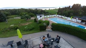 a woman sitting on a couch next to a swimming pool at Auberge de nos Aieux in Les Éboulements