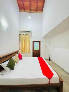 a bedroom with a large white bed with red accents at senlin villa in Galle
