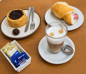 a table with plates of food with a drink and bread at Mala & Café in Curitiba