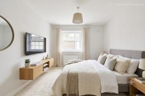 a white bedroom with a bed and a couch at Ramsey Rooms in Huntingdon