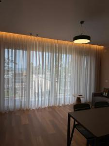 a living room with a large window with white curtains at Rrode Apartment Tale Beach in (( Shën Ded Gjoni ))