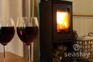 two glasses of wine sitting on a table in front of a fireplace at The Gatehouse Lodge Farm Stay, Distant Sea Views in Deal