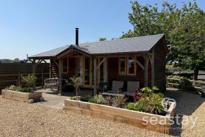 a log cabin with a porch and some plants at The Gatehouse Lodge Farm Stay, Distant Sea Views in Deal