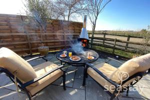 a patio with a table and chairs and a fire pit at The Gatehouse Lodge Farm Stay, Distant Sea Views in Deal