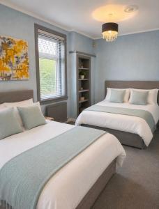 a bedroom with two beds and a chandelier at Rose Cottage Edinburgh in Edinburgh