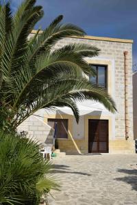 a house with a palm tree in front of it at Appartamenti la Pinetina di Favignana in Favignana