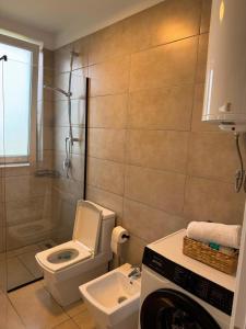 a bathroom with a toilet and a sink and a washing machine at Rrode Apartment Tale Beach in (( Shën Ded Gjoni )) +13 photos