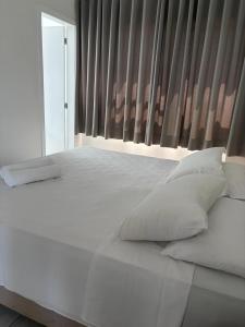 a white bed with white pillows and a window at Hotel Itajaí Tur - Itajaí Navegantes in Itajaí