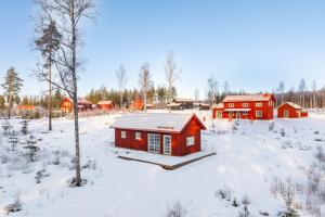 a red house in a field with snow on the ground at Bluebirch Cabin in Tällberg