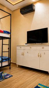 a living room with a television and a shelf at House Aisha Rooftop Hostel in Aourir