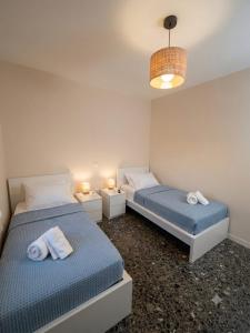 two beds in a room with two lamps and towels at LagonisiSunsetHouse in Kalívia Thorikoú