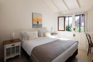 a white bedroom with a large bed and a window at Acassuso Suites in Acassuso