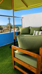 a green couch with an umbrella on a balcony at House Aisha Rooftop Hostel in Aourir