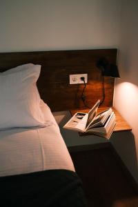 a bed with a nightstand with a book and a lamp at Togonidze's Wine Cellar in Telavi