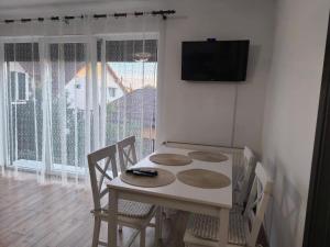 a dining room with a table and chairs and a television at Aero Comfort Apartment in Cluj-Napoca +4 photos
