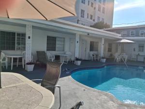 a swimming pool with chairs and an umbrella at Tropical Sky Ranch Motel in Clearwater Beach
