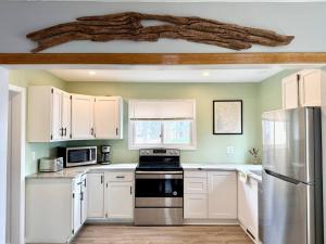 a kitchen with white cabinets and a stainless steel refrigerator at Cayuga lake cottage with private lake access in Washingtonville