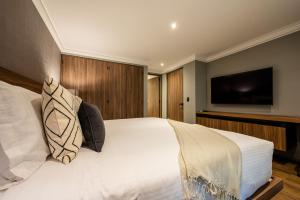 a bedroom with a white bed and a flat screen tv at Capitalia Obelisk Polanco in Mexico City +32 photos
