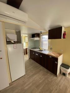 a kitchen with a white refrigerator and wooden floors at Beach Break Bungalows Playa El Palmar in Cádiz