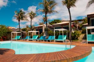 a swimming pool with blue chairs and palm trees at Poozendin Hotel de Charme in Canoa Quebrada