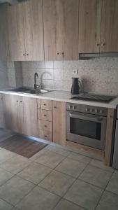 a kitchen with wooden cabinets and a sink and a stove at Calypso Rooms in Preveza