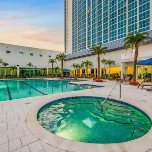 a pool at a hotel with palm trees and a building at Luxury Downtown Escape Pool, Spa and Cafe in Fort Myers