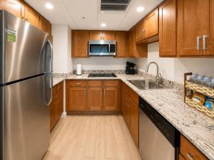a kitchen with wooden cabinets and a stainless steel refrigerator at Luxury Downtown Escape Pool, Spa and Cafe in Fort Myers