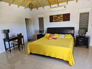 a bedroom with a bed with a yellow blanket and a desk at C'RENITY VILLA in Cul de Sac +41 photos