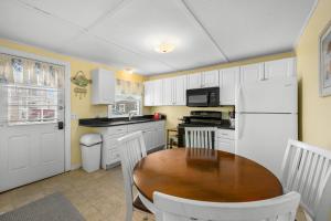 a kitchen with a wooden table and a white refrigerator at East Sandwich Beachfront Retreat in East Sandwich