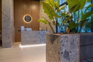 a lobby with plants in a large concrete planter at South Inn Marina Hotel in Vlorë