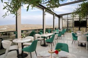 a restaurant with green chairs and tables and windows at KH La Maison in Abha