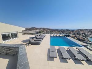 an outdoor swimming pool with lounge chairs and a swimming pool at PETRA Luxury Villas in Agioi Apostoli
