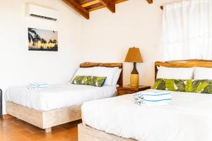 two beds in a room with white walls and wooden ceilings at Hotel Playa Cambutal in Cambutal +40 photos