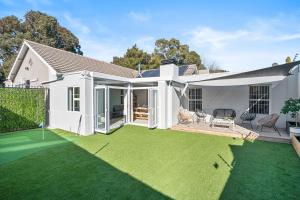 a white house with a yard with green grass at Sangrove Residence in Cape Town