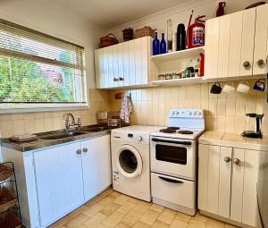 a kitchen with white cabinets and a washer and dryer at Bay Vista Garden Flat in Glencairn