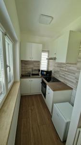 a kitchen with white cabinets and a wooden floor at Villa Epi in Sperlonga