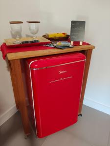 a red refrigerator under a wooden table with a counter at Suíte Arvoredo in Saquarema