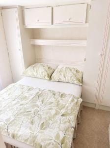 a bed in a small room with white cabinets at Chatka w środku lasu in Czerwona Wola