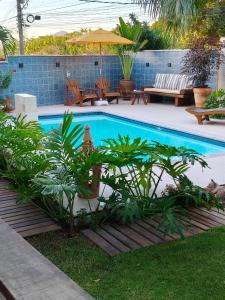 a swimming pool with plants and an umbrella at Suíte Arvoredo in Saquarema