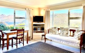 a living room with a table and a couch and a desk at Bay Vista Garden Flat in Glencairn