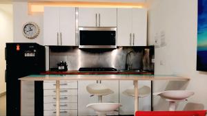 a kitchen with white cabinets and a counter with stools at Hotel Beach Pool Punta Cana Vacation in Punta Cana