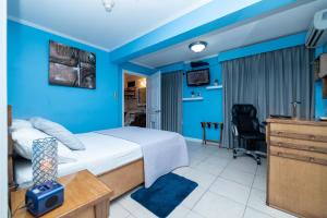 a bedroom with blue walls and a bed and a desk at Culture Crossroads Inn in Port-of-Spain