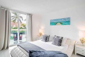a white bedroom with a bed and a large window at Luxury Miami Condos - 1BR-2BR & 3BR in Miami Beach +169 photos