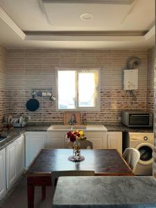 a kitchen with a table with a vase of flowers on it at sunset apartment in Kelibia