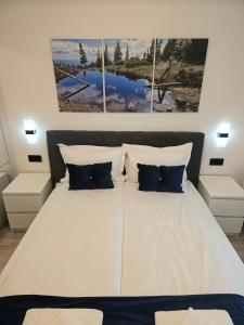 a bedroom with a white bed with three paintings on the wall at Apartament Fodor in Topliţa
