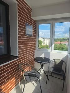 a balcony with two chairs and a table and two windows at Apartament Fodor in Topliţa